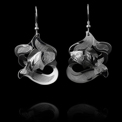 The Salmon earrings are made using sterling silver and have abstract hangs depicting the Salmon legend in ocean waves. The waves are made with cutout pieces and the salmon is set in the front of then. There are carvings made on the piece depicting the scene.