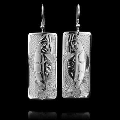 These Salmon earrings are made from sterling silver and have wide, rectangle hangs. There are carvings on the surface of the hangs depicting a side view on an entire Salmon.