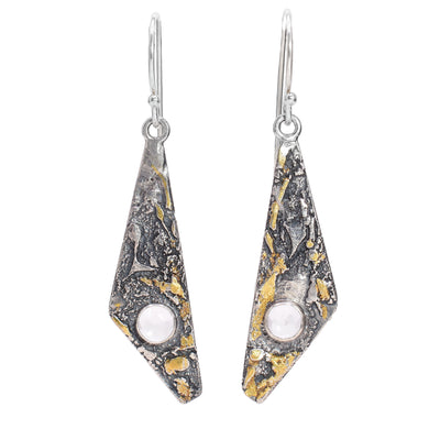 These sterling silver dangle earrings have long, triangle shaped hangs with 24K gold highlights. At the bottom of the hangs are white quartz gemstones.