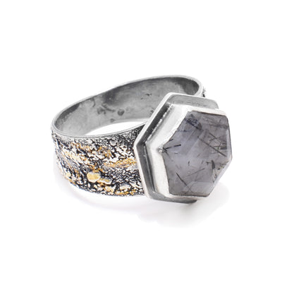 This sterling silver hexagon ring has a wide, textured band with 24K gold highlights. The embellishment is a hexagon tourmaline rutilated quartz wrapped in silver.