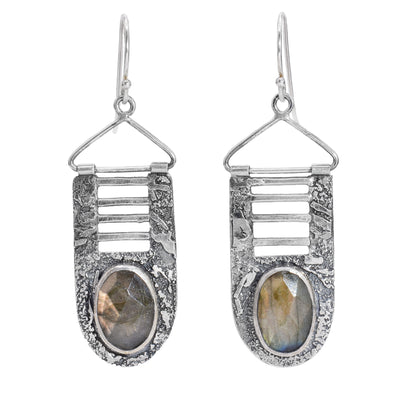 These sterling silver dangle earrings have large hangs with a textured surface. At the bottom of the hangs are large labradorite gems and above them are four vertical cutouts.