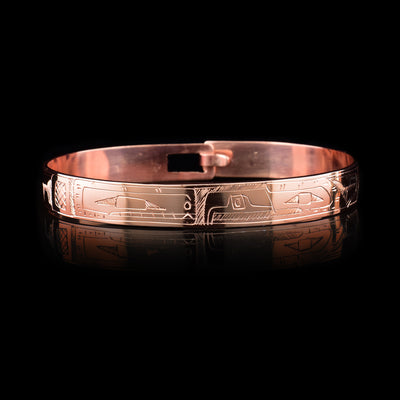 This copper bangle bracelet has a single, thin band with a simple hook clasp in the back. There is a depiction of the Orca and the Eagle that have been beautifully carved into the surface of the band. The heads of the legends meet and are facing each other at the top of the band.