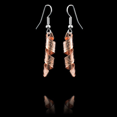 These spiral earrings have hangs made from copper bands that have been curved into horizontal spirals. The copper cylinders drop down and there are depictions of the Eagle carved into them with their beaks facing upwards.