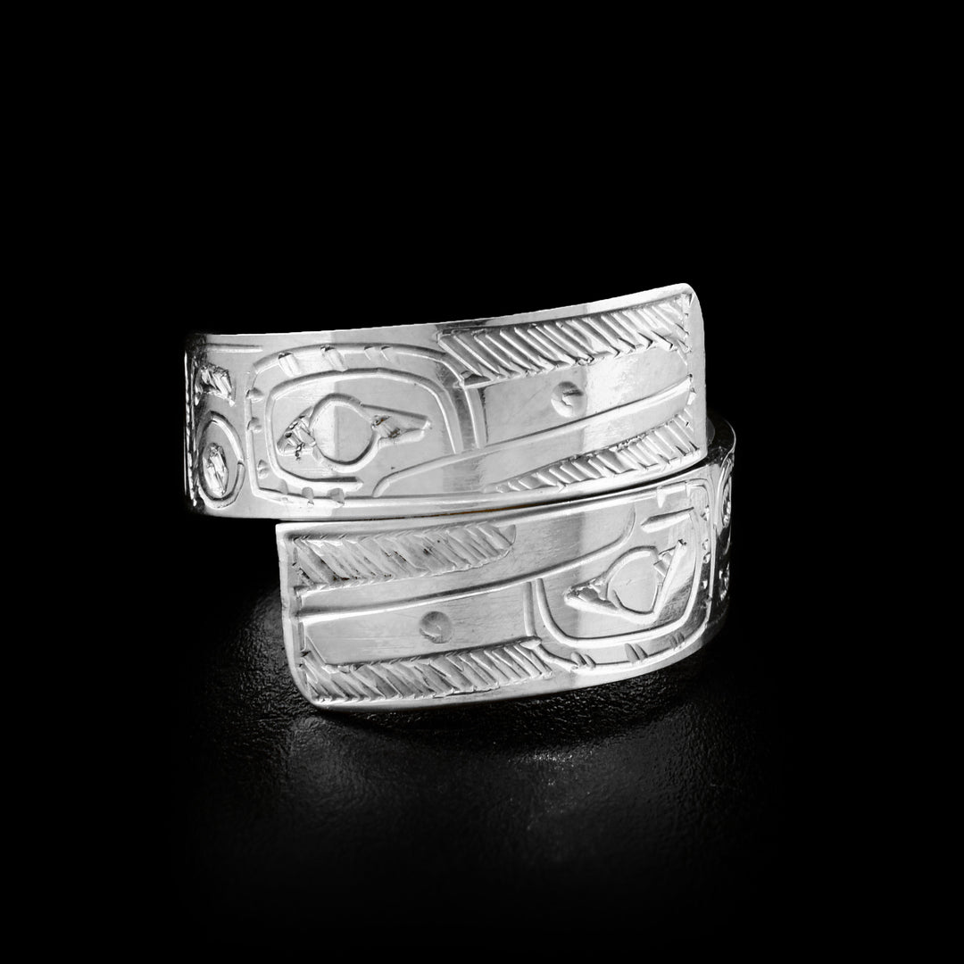 This wrap around ring is made out of a sterling silver strip that has two Hummingbird faces carved on the front, where the ends of the ring overlap. The face of the lower Hummingbird is upside down.