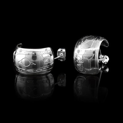 These wide hoop earrings are made from sterling silver and have a single, wide band with a gap in the back. There are carvings on the surface of the hoops depicting the Bear.