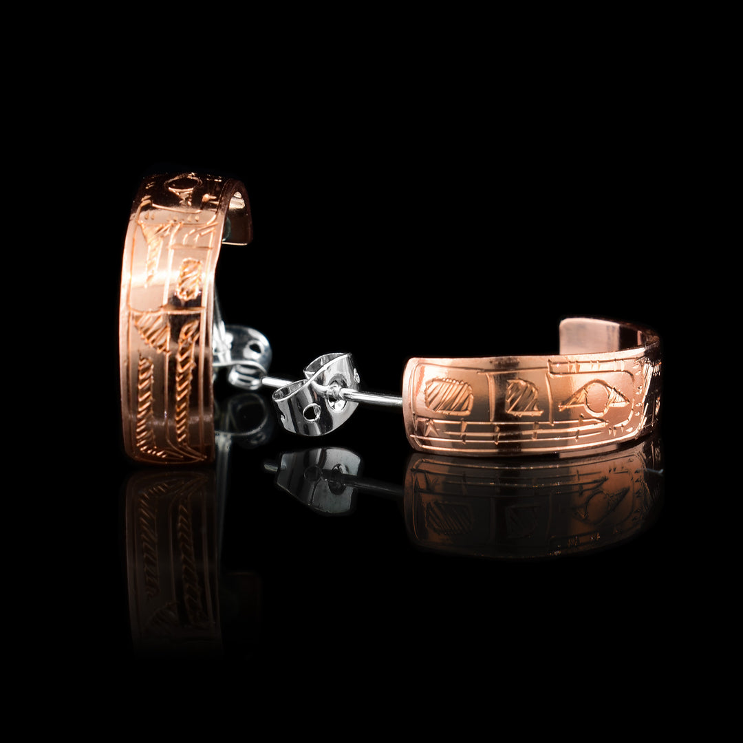 These stud hoop earrings are made from copper and have wide bands curved into a hoop with a gap in the back. There are depictions of the Wolf carved into the surface of the band. The head of the Wolf is facing the hooks.