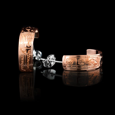 These stud hoop earrings are made from copper and have wide bands curved into a hoop with a gap in the back. There are depictions of the Wolf carved into the surface of the band. The head of the Wolf is facing the hooks.