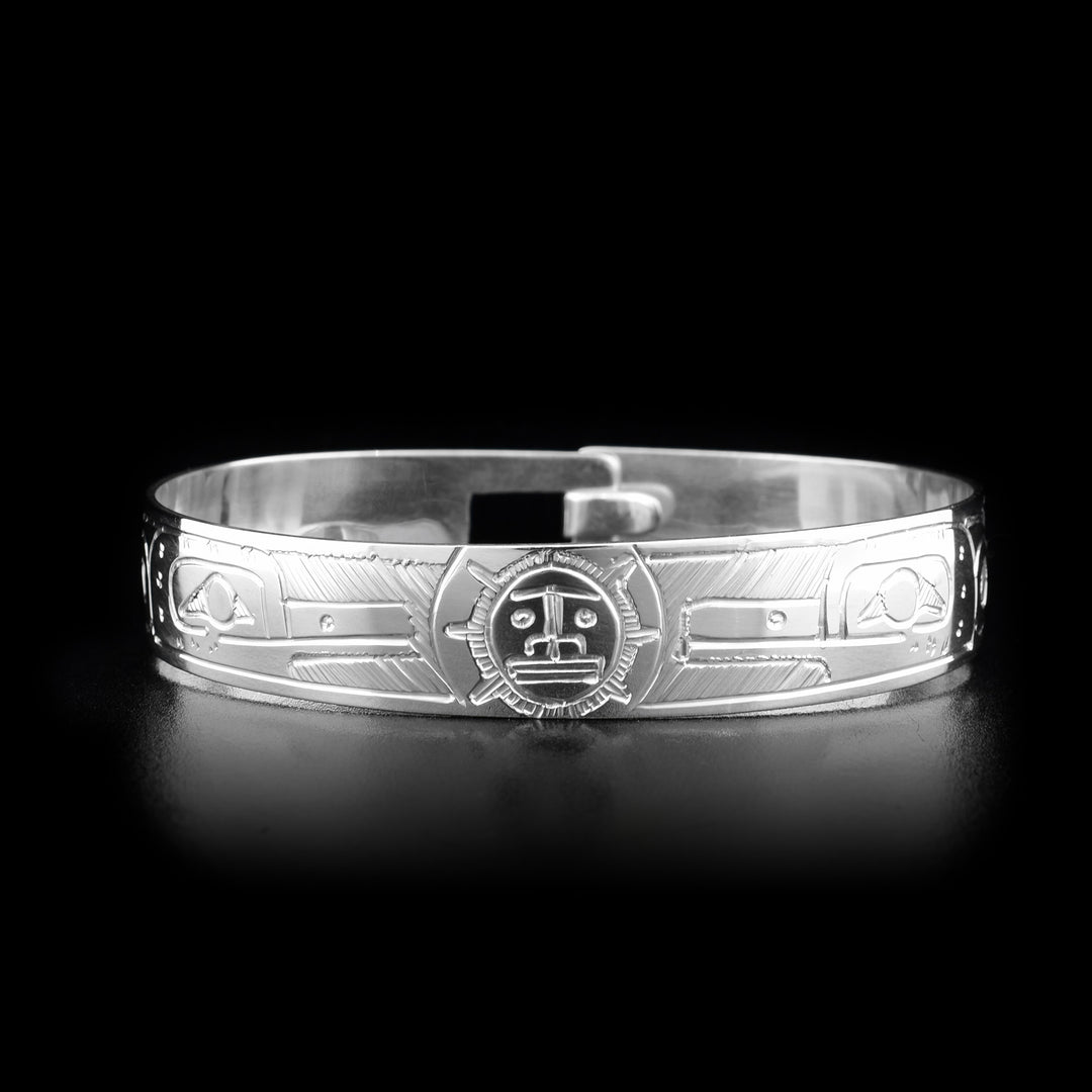 This sterling silver clasp bracelet has two depictions of the Hummingbird and a depiction of the Sun carved into the band. The Hummingbirds are depicted facing the Sun and there is a clasp at the back of the bracelet.