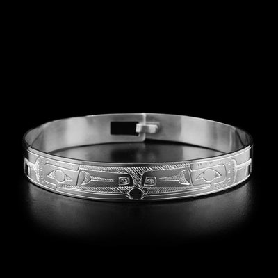 This sterling silver bracelet depicts two Raven heads facing each other, holding the Sun in their beaks. The bodies of the Ravens are engraved around the rest of the bracelet. There is a clasp on the back.