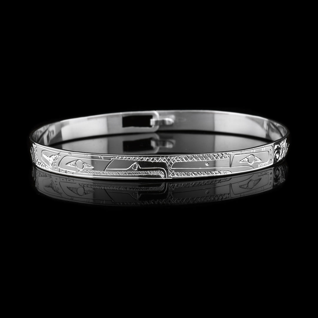 This dainty Eagle and Hummingbird bracelet has a thin, sterling silver band with a clasp in the back. There are depictions of the Eagle and the Hummingbird carved into the surface of the band. The legends are depicted facing each other. 