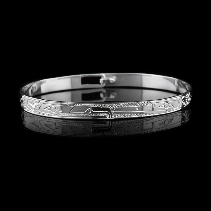 This dainty Eagle and Hummingbird bracelet has a thin, sterling silver band with a clasp in the back. There are depictions of the Eagle and the Hummingbird carved into the surface of the band. The legends are depicted facing each other. 
