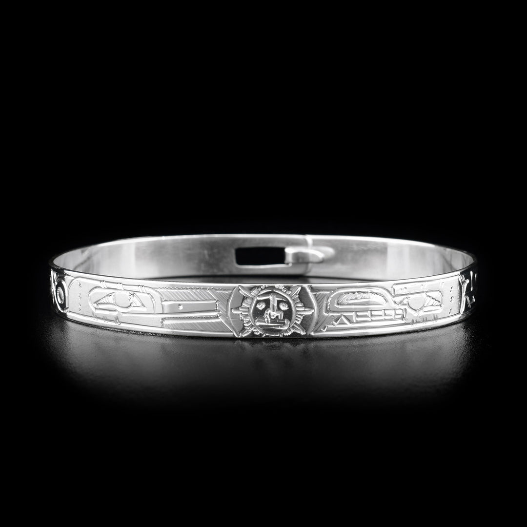 This sterling silver clasp bracelet has depictions of the Hummingbird, the Bear, and the Sun carved into the band. The Sun is depicted at the top of the bracelet and there is a clasp in the back.