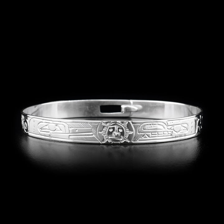This sterling silver clasp bracelet has depictions of the Hummingbird, the Bear, and the Sun carved into the band. The Sun is depicted at the top of the bracelet and there is a clasp in the back.