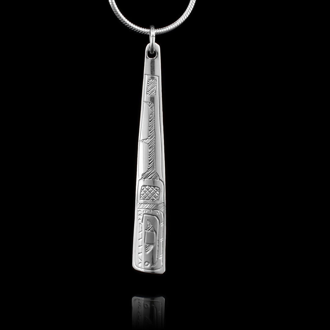 This Orca pendant is made from sterling silver and is shaped like a long, thin triangle. There is a depiction of the Orca carved into the surface of the pendant.