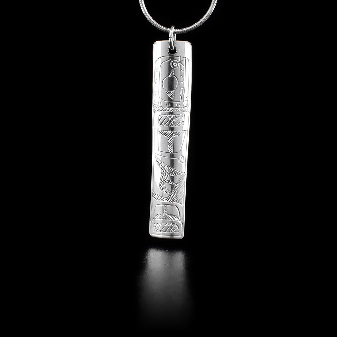 This sterling silver pendant is long, thin, and rectangular. There is a depiction of the Orca carved into it.