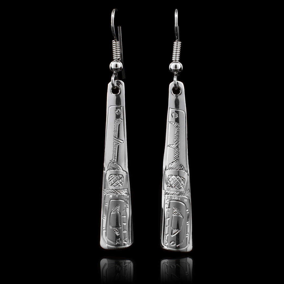 These dangling Orca earrings are made from sterling silver and have long, thin and tapered hangs. There are carvings on the surface of the hangs depicting the Orca.