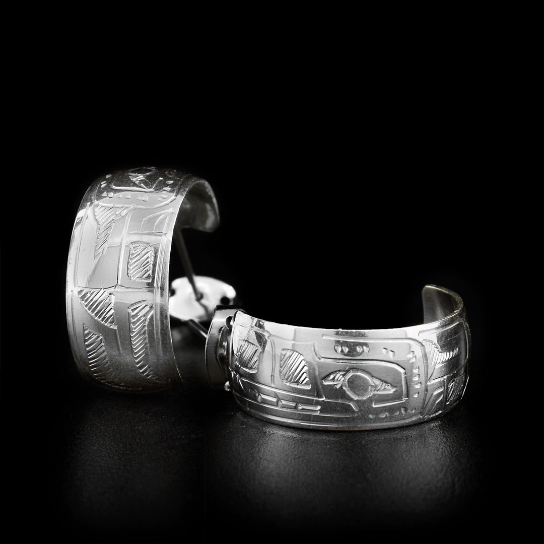 These wide hoop earrings are made out of sterling silver. The earrings have a carved face of the Wolf on them.