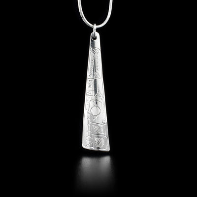 This sterling silver pendant is long, thin. and wider at the bottom. There is a depiction of the Wolf carved into it.