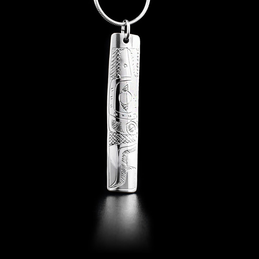 This sterling silver pendant is long, thin, and rectangular. There is a depiction of the Hummingbird carved into it.