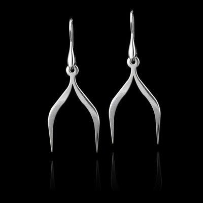 These sterling silver dangling earrings have thin hangs that depict a Haida Gwaii character.