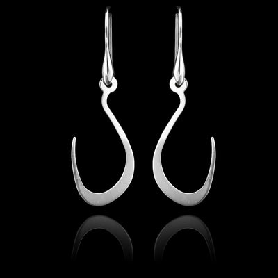 These sterling silver long dangling earrings have thin hangs that drop down and curve upwards. The hangs depict a Haida Gwaii character.