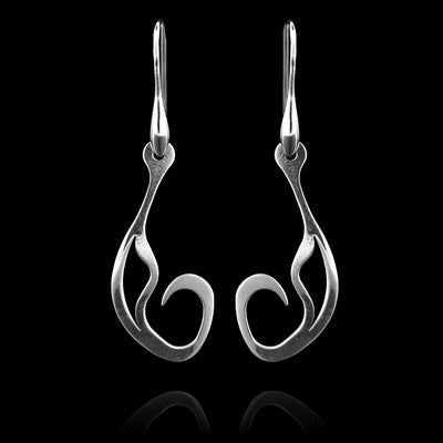 These sterling silver dangling earrings have thin hangs that drop down and have a teardrop shaped design at the bottom. The ends of the piece curve up at the bottom into a spiral design. The hangs depict a Haida Gwaii character.