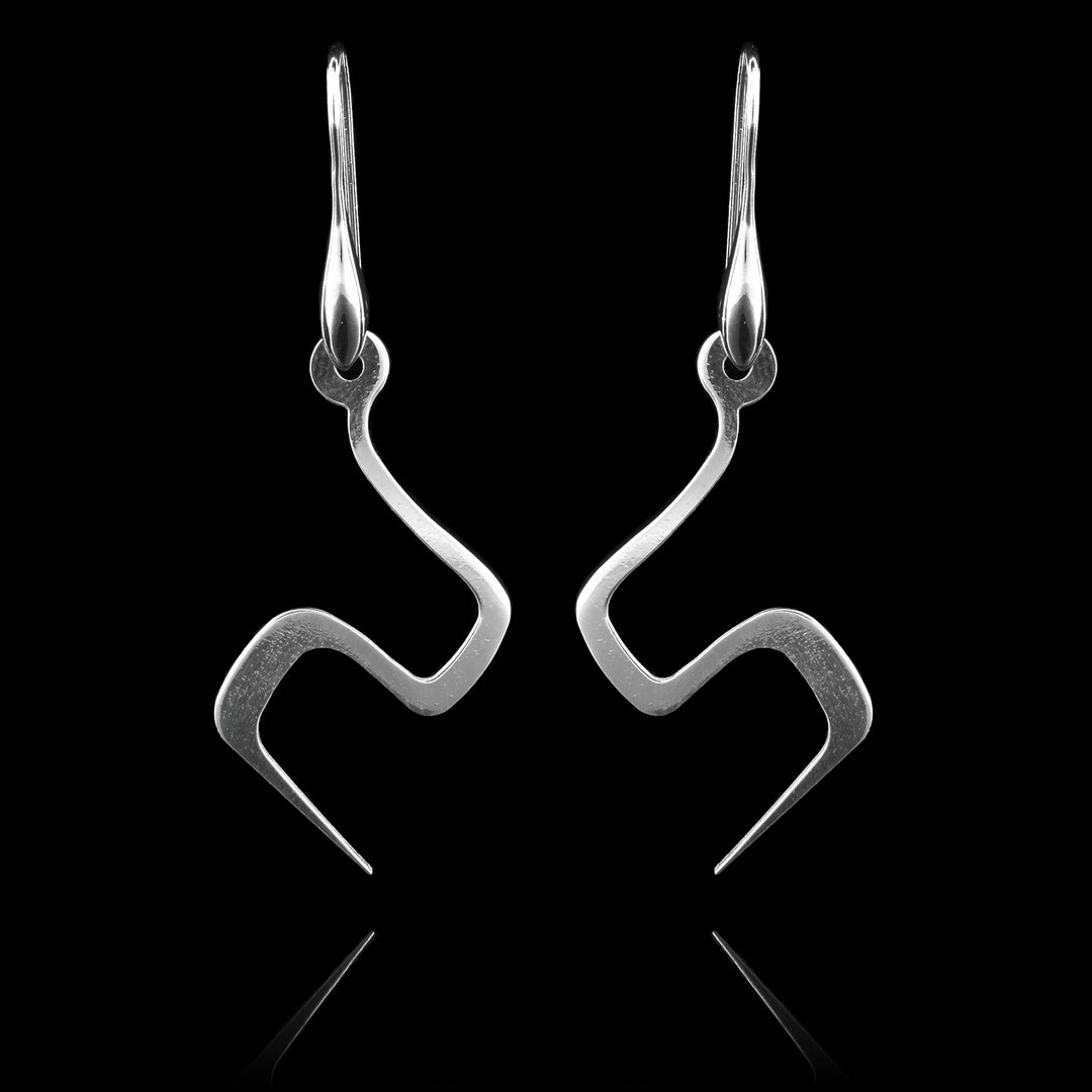 These sterling silver dangling earrings have thin hangs that drop down and turns in a large zig-zag. The hangs depict a Haida Gwaii character.