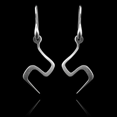 These sterling silver dangling earrings have thin hangs that drop down and turns in a large zig-zag. The hangs depict a Haida Gwaii character.