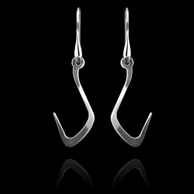 These sterling silver long dangling earrings have thin hangs that drop down and curve upwards. The hangs depict a Haida Gwaii character.