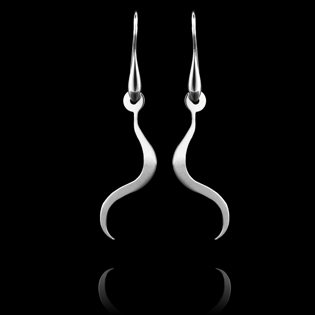 These sterling silver long dangling earrings have thin hangs that drop down and curve. The hangs depict a Haida Gwaii character.