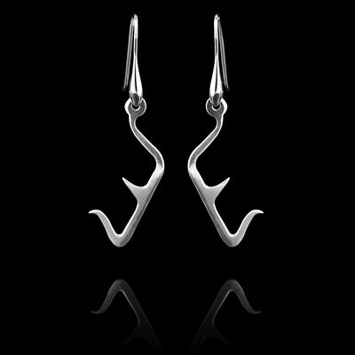 These sterling silver long dangling earrings have thin hangs that drop down and have points protruding from them. The hangs depict a Haida Gwaii character.