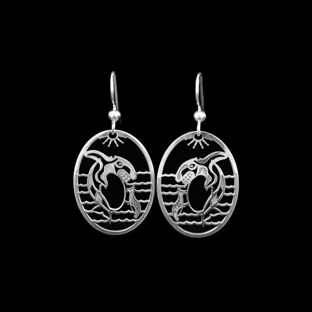 These Orca whale earrings are made from sterling silver and the hangs are oval shaped. There are cutout depictions of the Orca and waves that have been cast into the hangs.