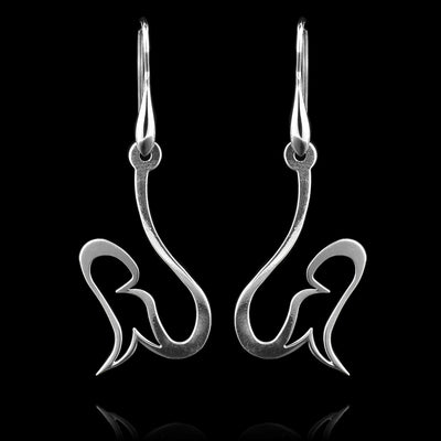 These sterling silver dangling earrings have thin hangs that drop down and have a teardrop shaped design at the bottom. The hangs resemble hooks. The hangs depict a Haida Gwaii character.