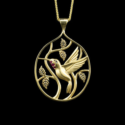14K yellow gold pendant with hummingbird and vines. Bird has three rubies set in throat. Cut out background. Handcrafted by Dennis Kangasniemi.