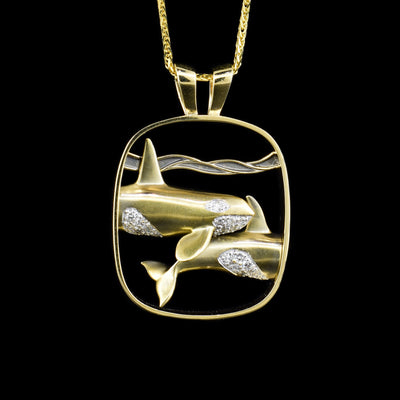 14K yellow and white gold pendant featuring diamond-encrusted orcas swimming underwater. Cut out background. Handcrafted by Dennis Kangasniemi.