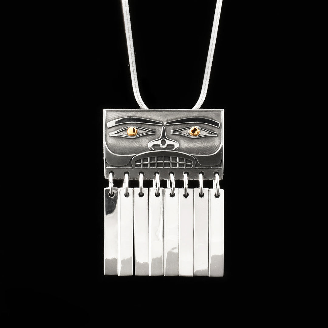 This 18K gold and silver pendant has rectangular face and flat silver bars hanging below. Pupils are 18K yellow gold and rest of piece is sterling silver. Hidden bail on back.