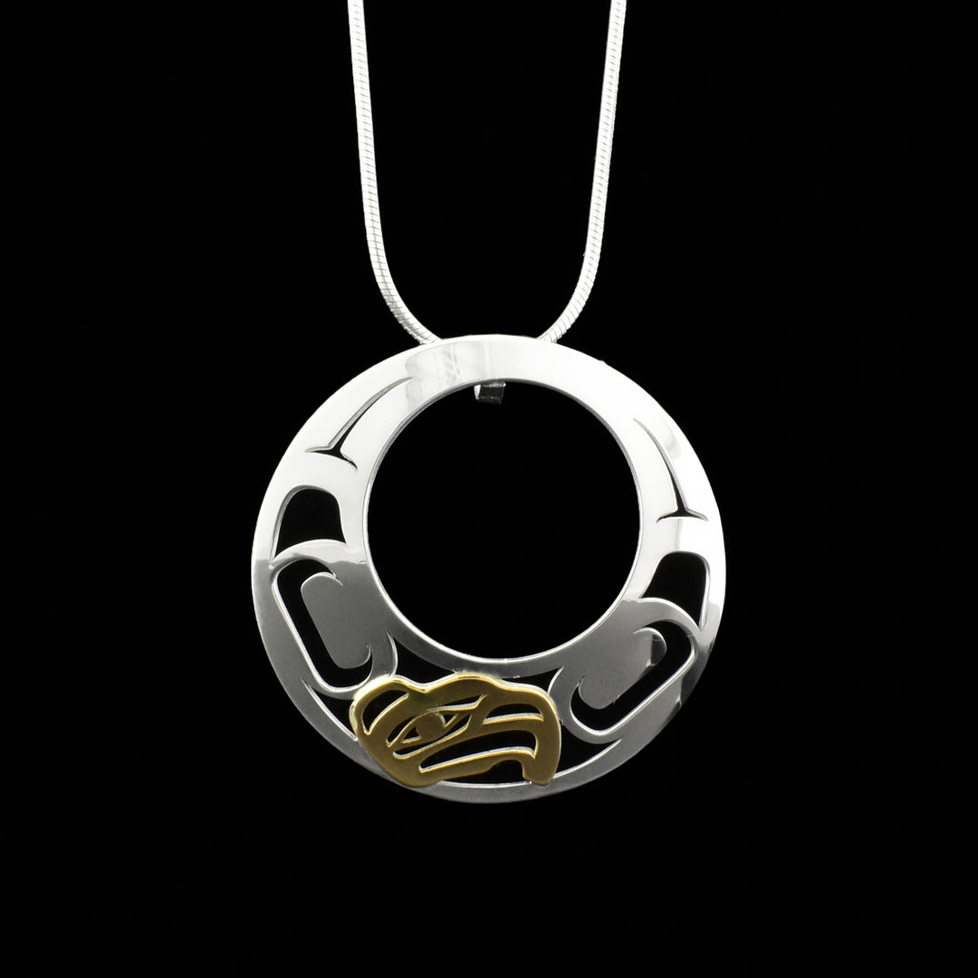 Sterling silver round 18K gold Eagle pendant with circle cut out. 18K yellow gold eagle head on right-bottom facing left. Cut out designs on both sides of eagle’s head. Hidden bail on back.