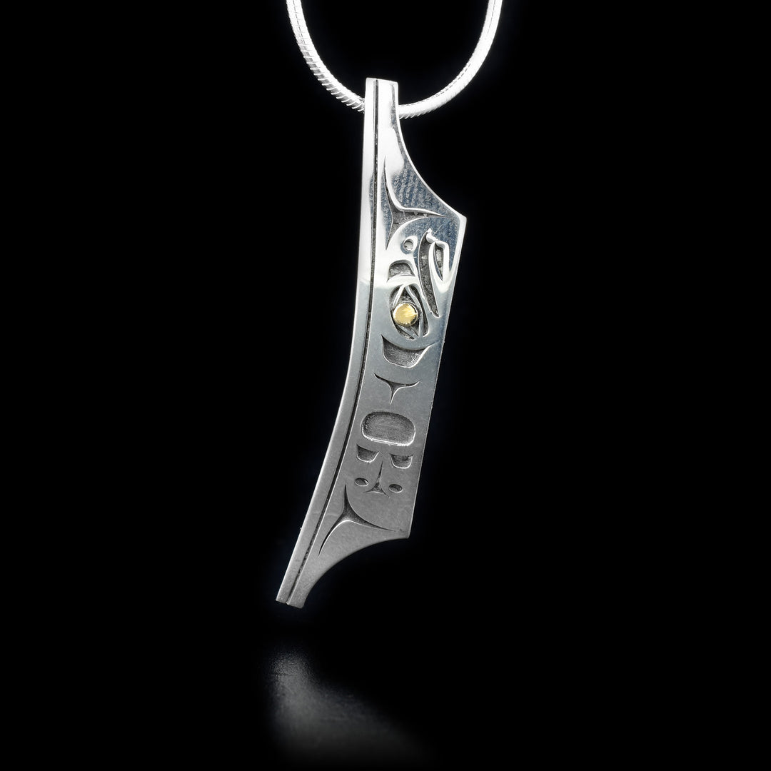 This sterling silver pendant is shaped like a canoe and there is a depiction of the Eagle cutout from the surface of the pendant. The eyes of the Eagle are made from 18K gold.
