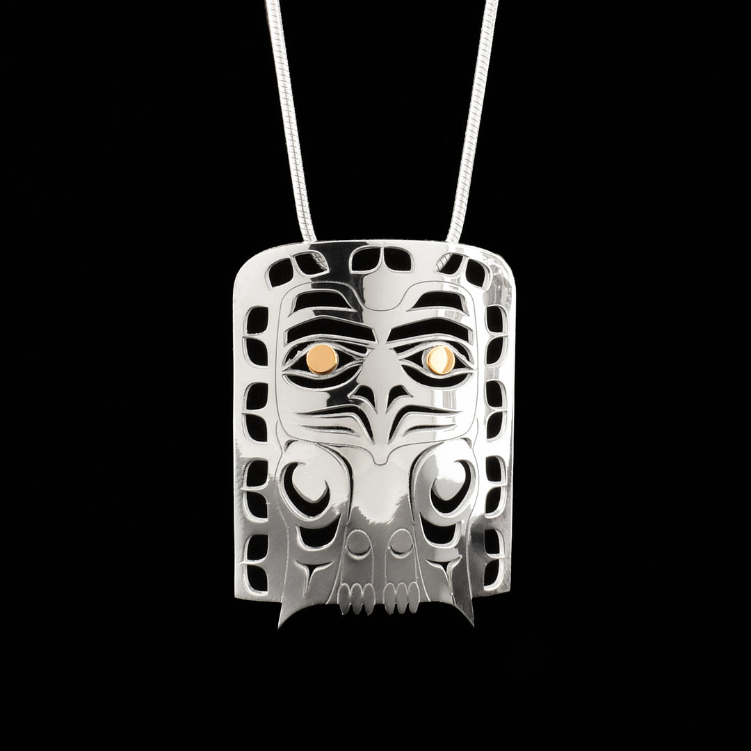 This sterling silver and 18K gold Eagle pendant is large and rectangular. There is a depiction of the Eagle and other designs cast into the surface of the pendant. The eyes of the Eagle are made from 18K gold.