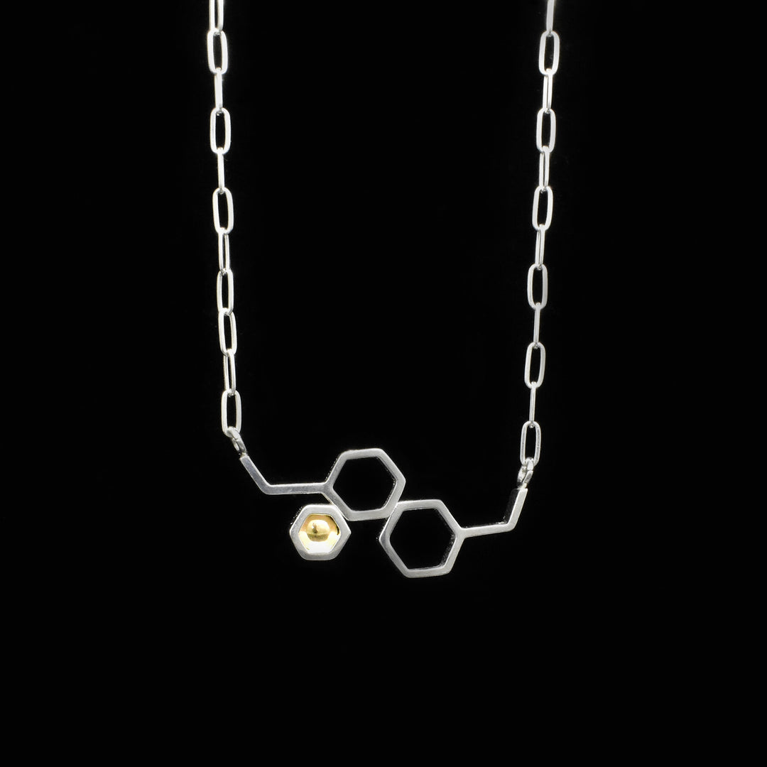 Bib necklace style. Made of sterling silver. Honeycomb design on central piece with 14K gold in one of the hexagons. 15.5” long with 2” extender.