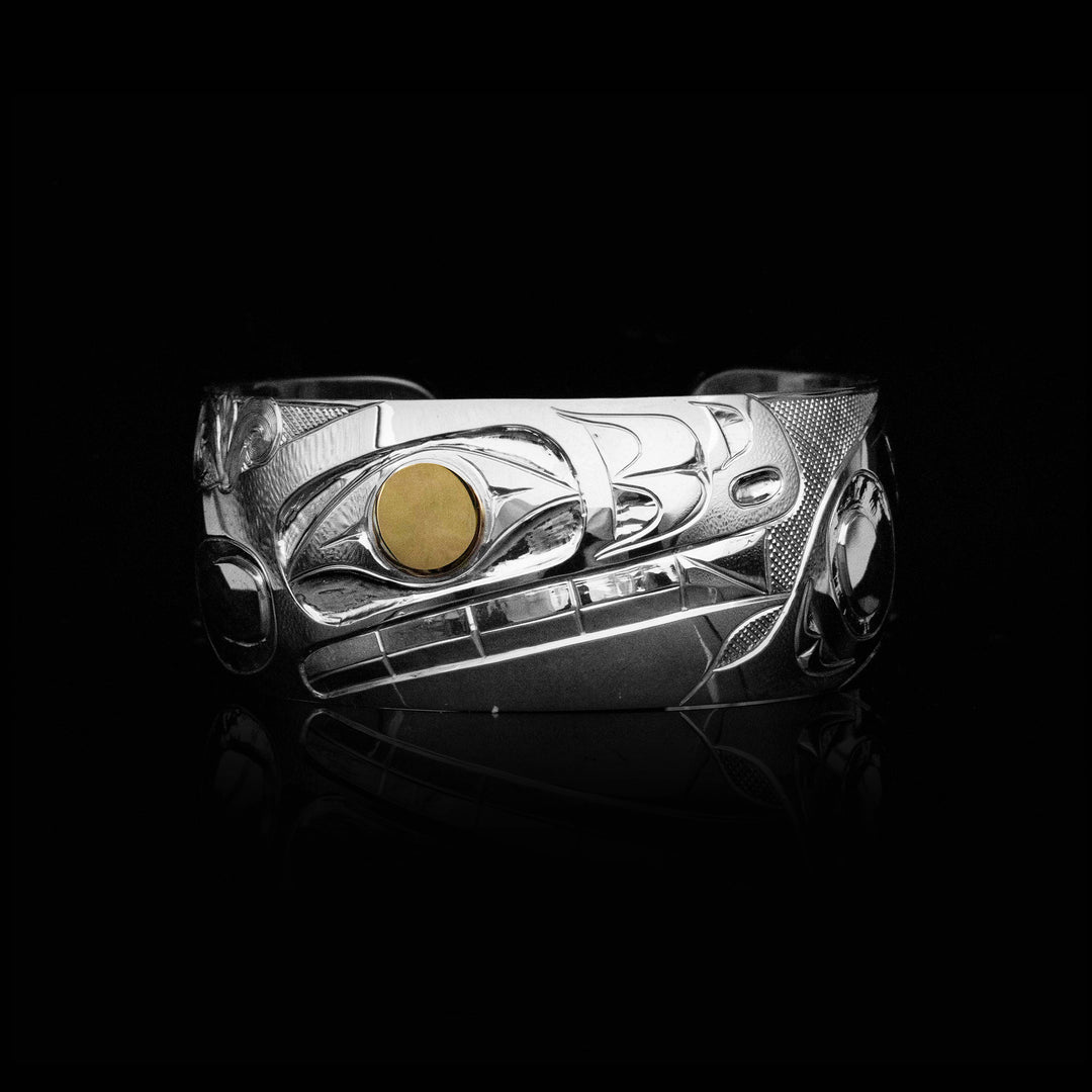 Orca head facing left, teeth showing. 14K gold in eye. Design done in ovoids and lines. Background is cross-hatching.