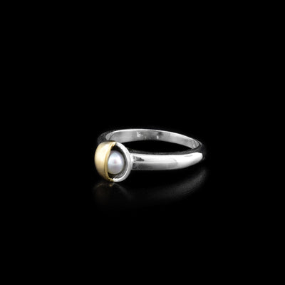 Sterling silver ring with white freshwater pearl on front set in bowl shape. Pearl is half covered by brushed 14K yellow gold on right.