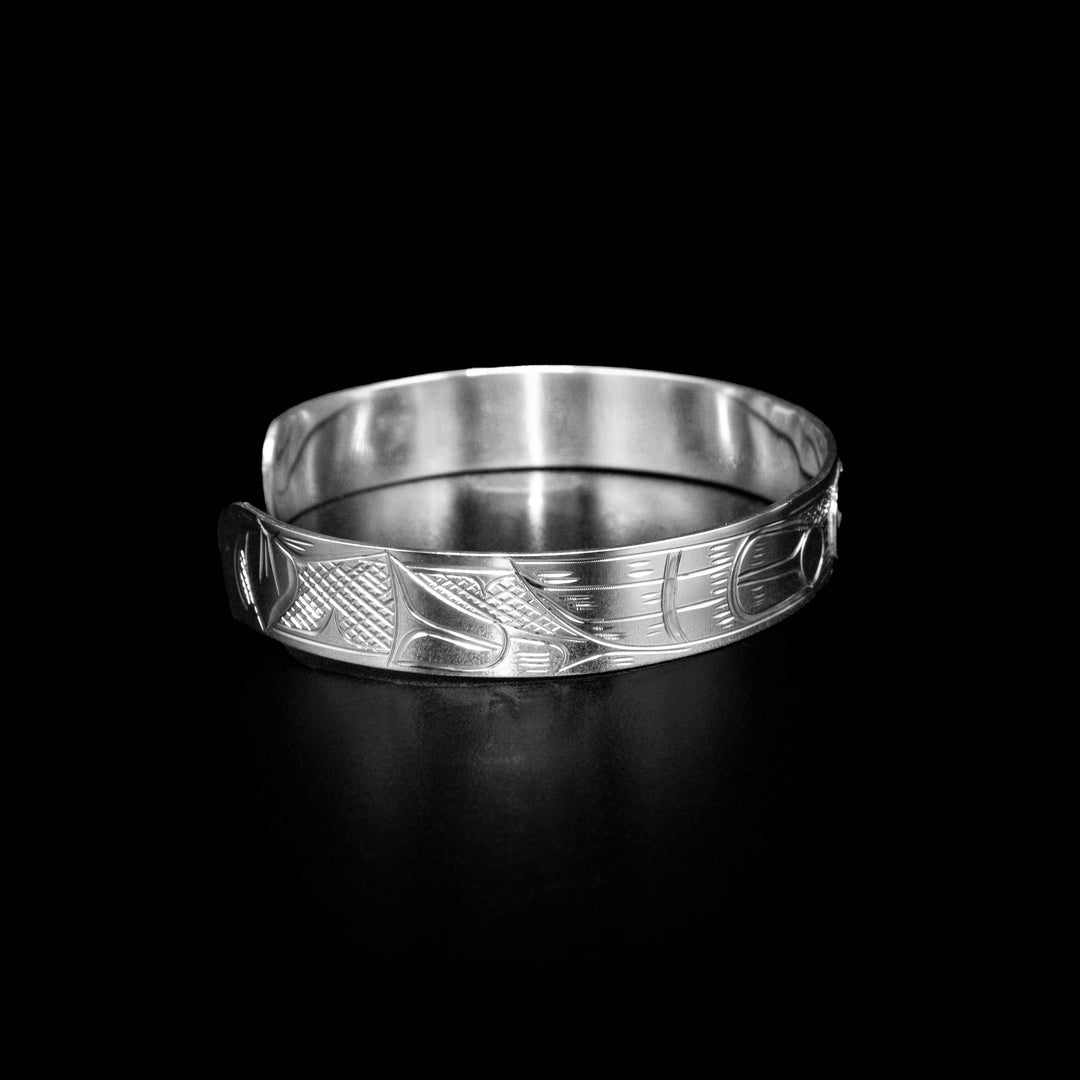 Right side of bracelet with hummingbird body and cross-hatching background. Flower at the end.