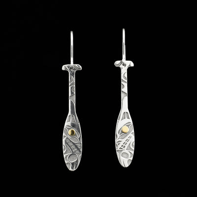 Dangle earrings in shape of Tahltan paddles. Both paddles have a side-view of a wolf’s head and a paw with designs above. 18K gold in the pupils.