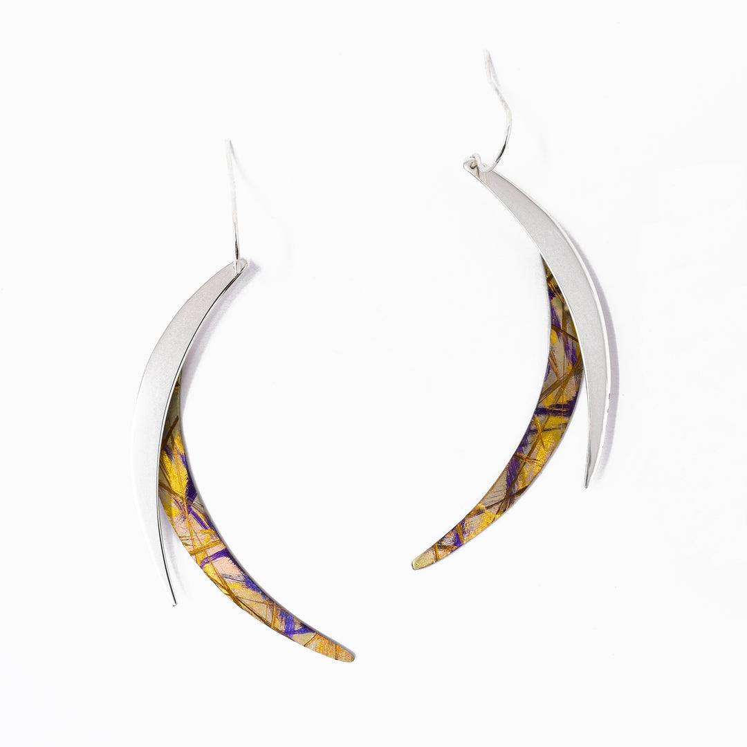These titanium earrings are in a swooping shape with one part gold anodized titanium and the other sterling silver.