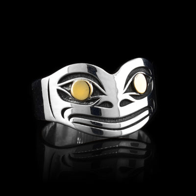 This wide Frog ring has been made using sterling silver and 14K gold and has a single band that becomes more wide at the top of it. There is a depiction of the head of the Frog that has been cast into the surface of the wide portion of the ring. The designs are deep and the eyes of the Frog are made using the gold.