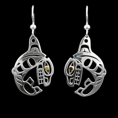These dangling Orca earrings are made from sterling silver and 14K gold. The hangs are shaped like and have cutouts on them depicting the Orca; the eyes of the legends are made from gold.