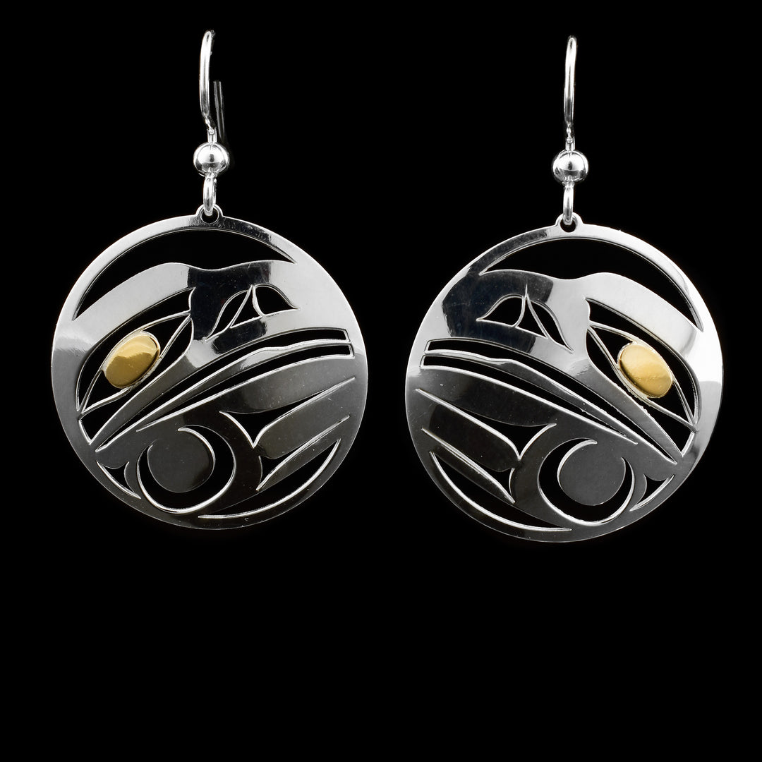 These dangling Raven earrings are made from sterling silver and 14K gold with circle shaped hangs. There are cutouts depicting Raven made into the surface of the hangs and the eyes are made from gold.