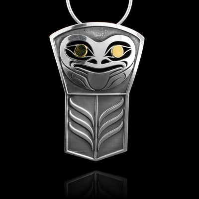 This Frog pendant has been made from sterling silver and 18K gold. The pendant is shaped like a shield and has designs cast into the surface of it including a depiction of the Frog. The large eyes of the Frog are made using the gold.