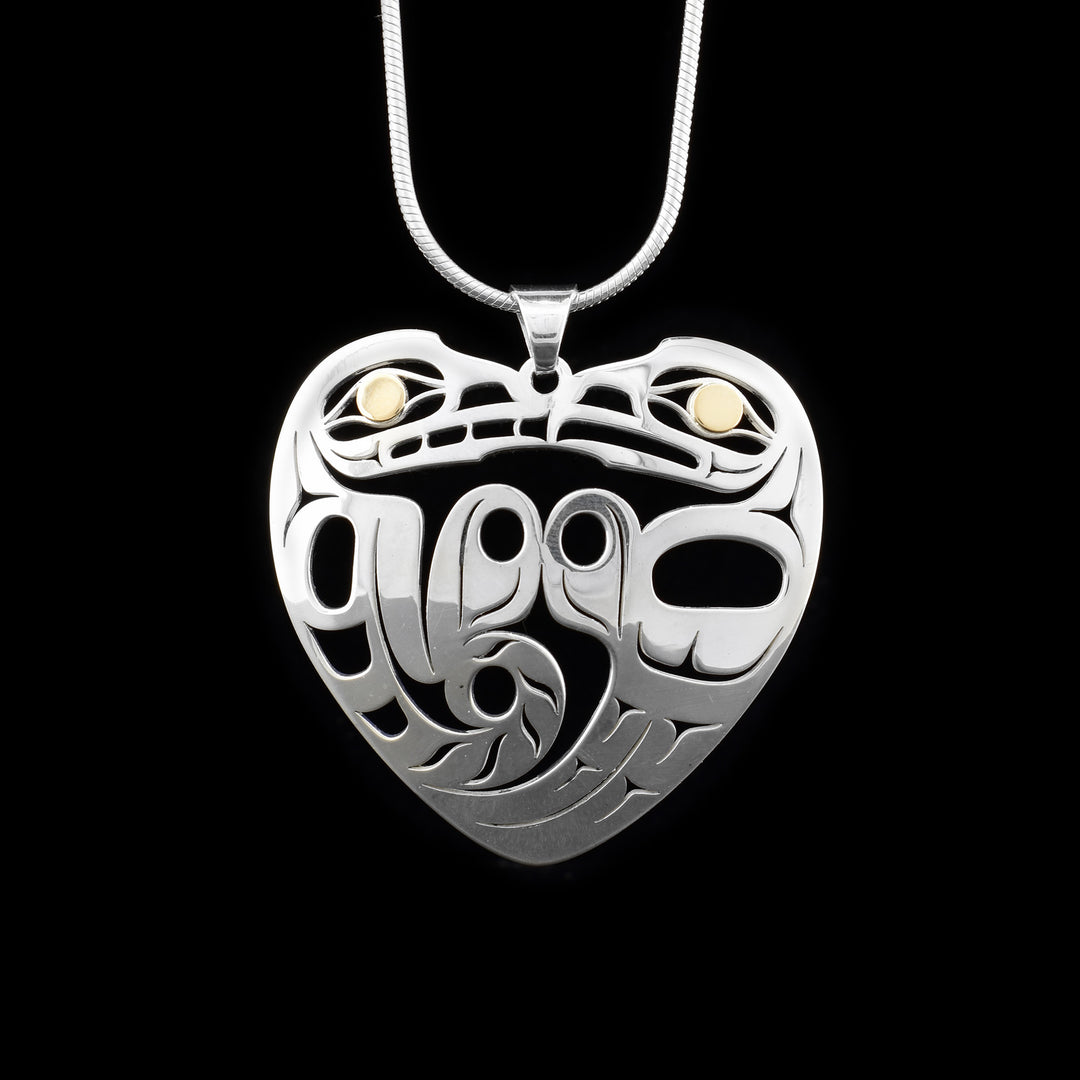 This Eagle and Wolf pendant depicts a side-view of sterling silver wolf and eagle facing each other, their shapes form a heart. Their features are laser-cut, leaving pierced out spaces. 18K yellow gold in both the visible eyes.